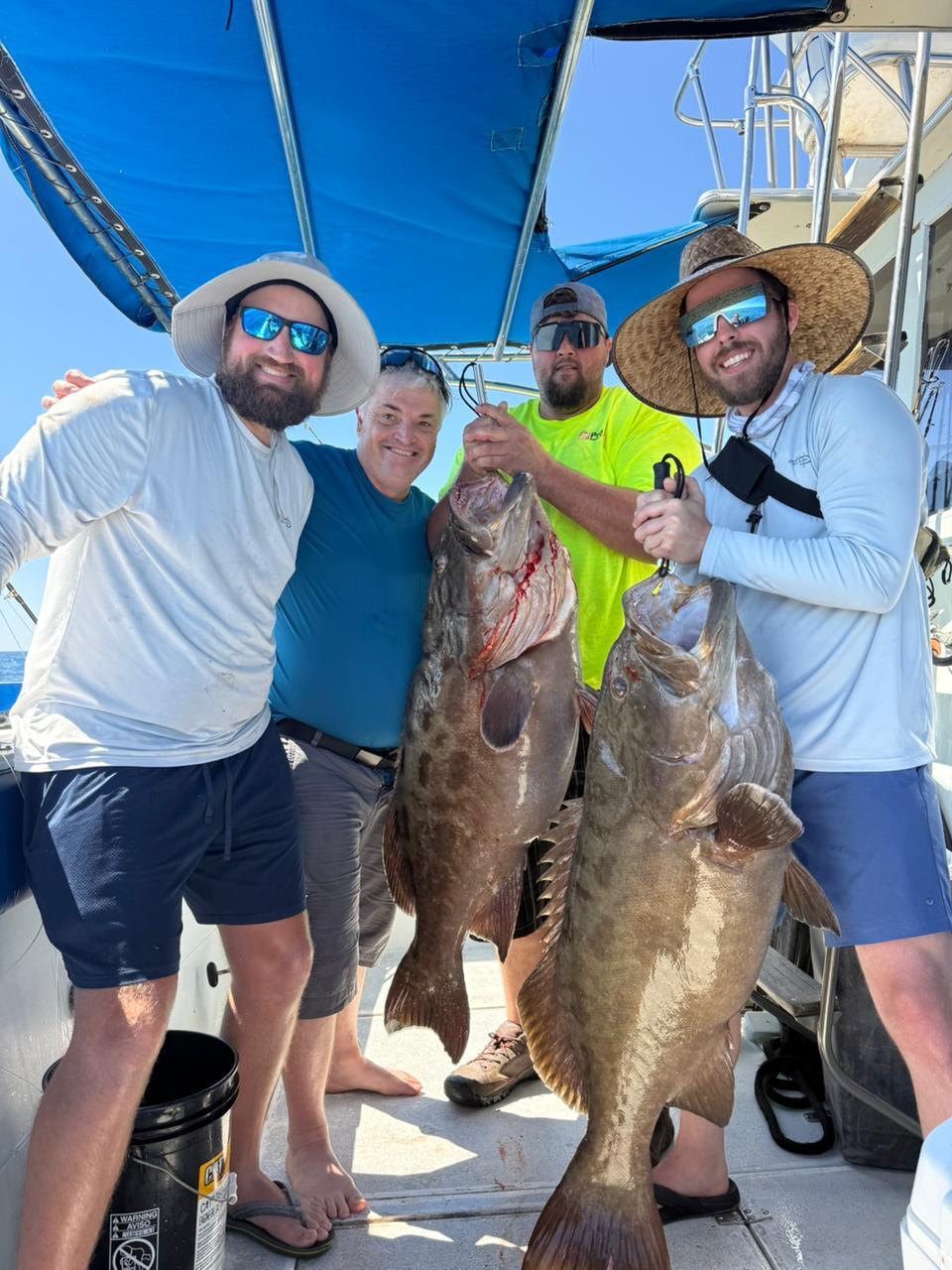 Anglers holding two large grouper caught near Rocky Point